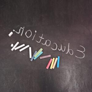 The word educatin written on a blackboard and various colors of chalk